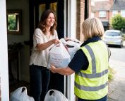 Woman donating bags of clothes to a We Recycle Clothes collector at her doorstep